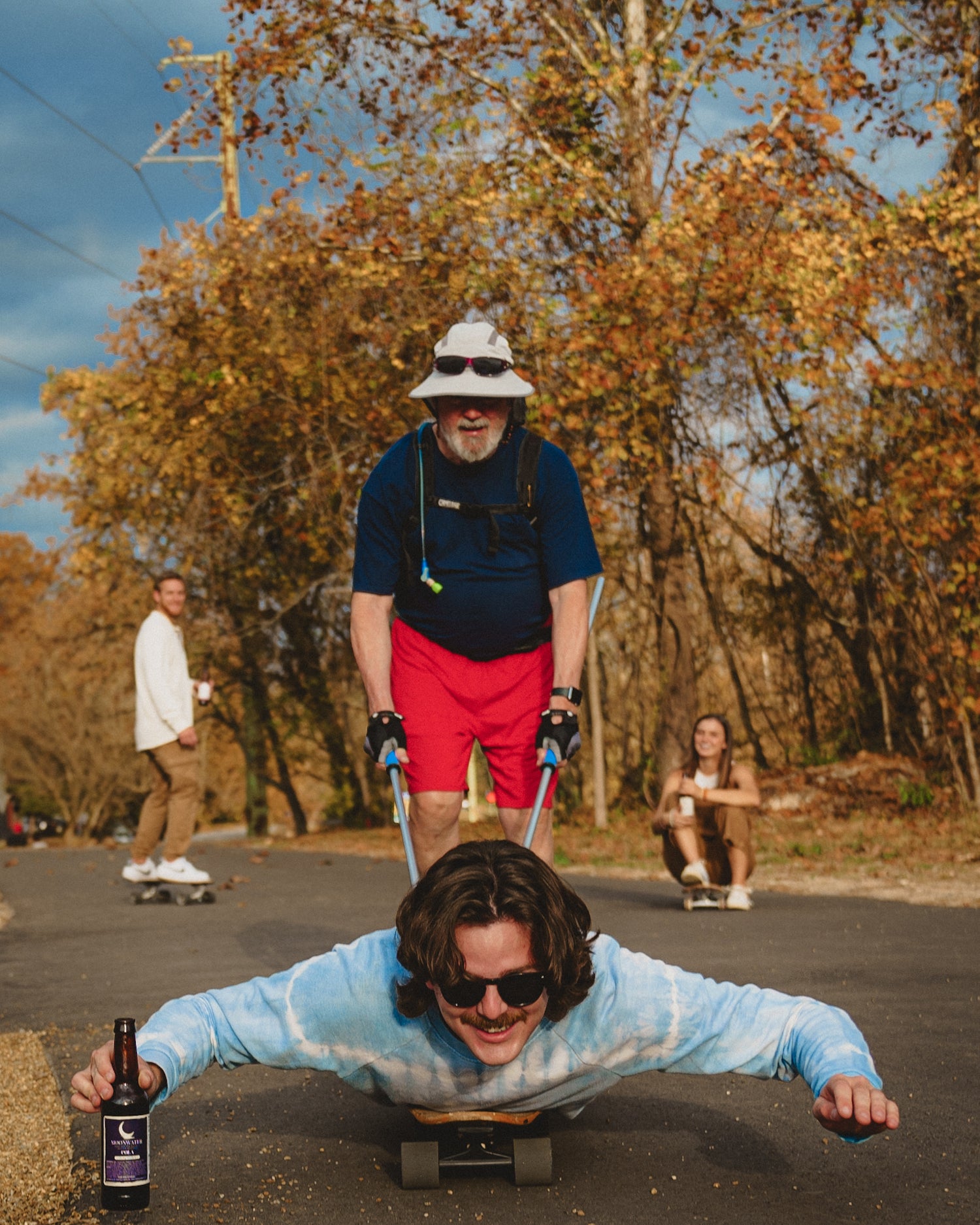 Older man pushing young man on skateboard holding a Moonwater beverage